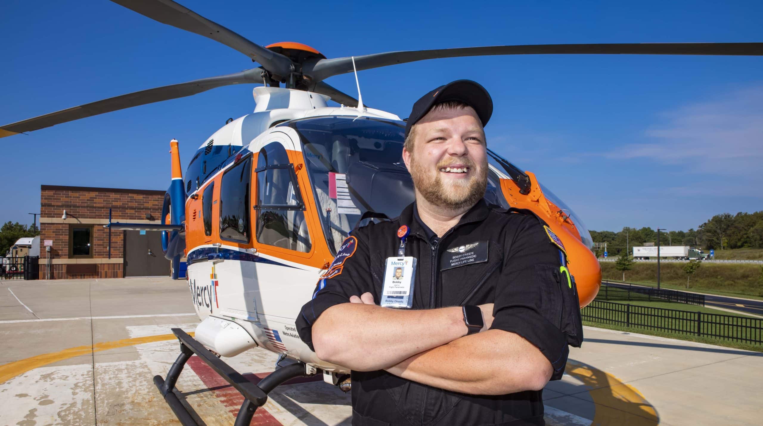 Bobby OKeefe stands in front of a Mercy Life Line Helicopter