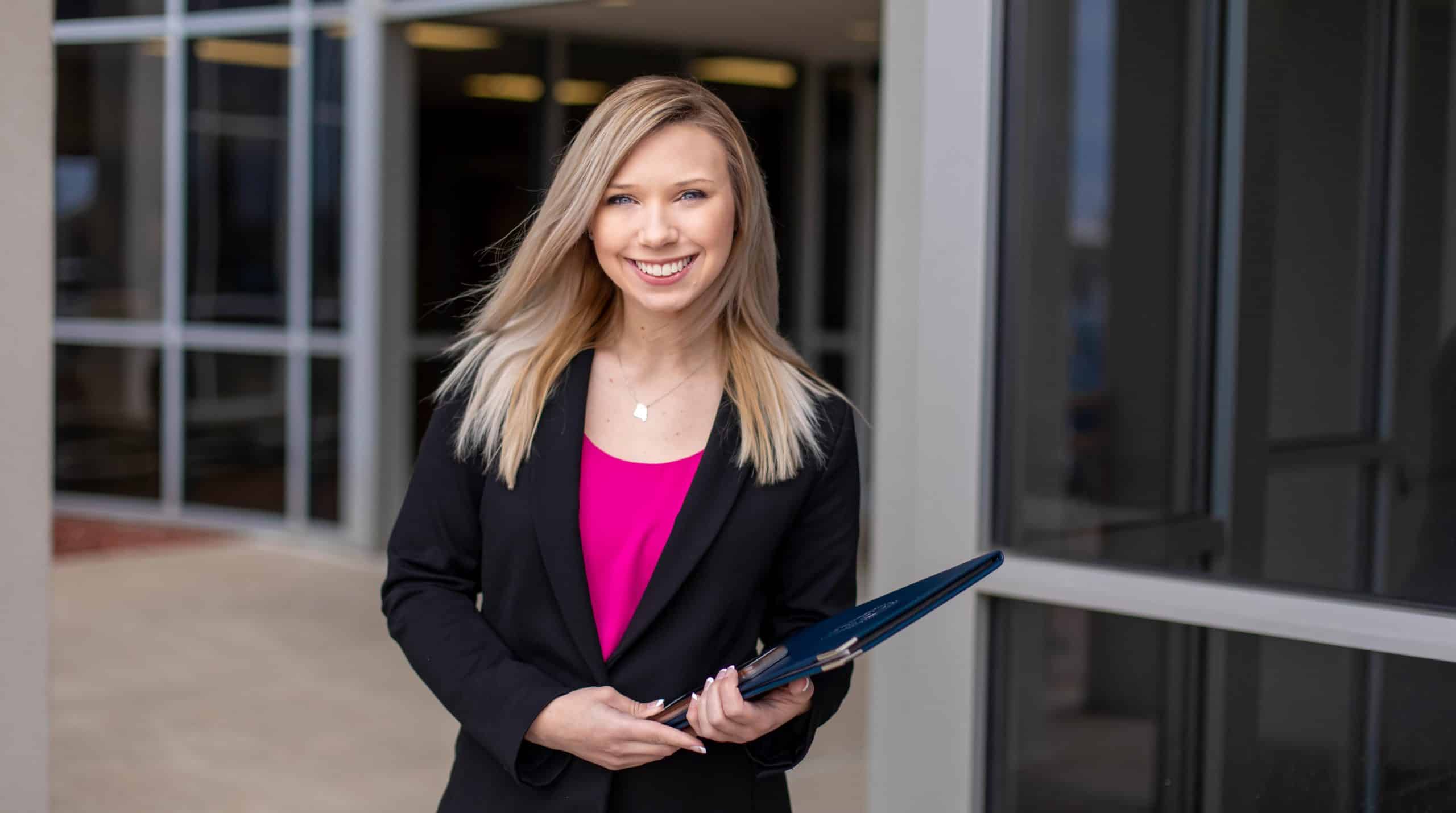 Student dressed in business professional attire, smiling at the camera.